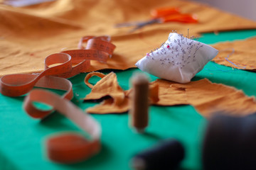 Flexible measuring tape and needle pad on the seamstress table. Seamstress tools. Shallow depth of...