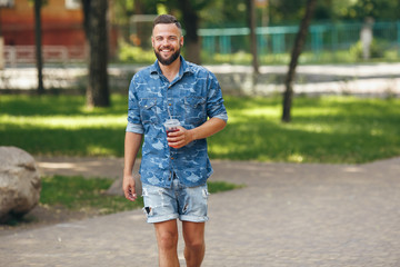 A young guy walking in the park with lemonade in the spring. Spring day.