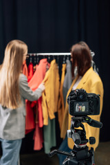 selective focus of digital camera with stylist touching trendy clothing near model on screen