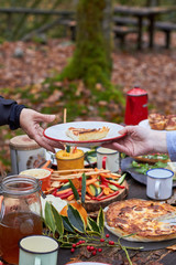servir plato en manos picnic de otoño al aire libre sobre mesa rústica