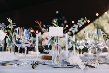 Wedding decor in blue and gray. Banquet tables with tablecloths are decorated with compositions of flowers, on the tables are plates, glasses and candles