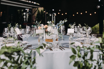 Wedding decor in blue and gray. Banquet tables with tablecloths are decorated with compositions of flowers, on the tables are plates, glasses and candles