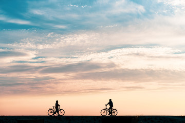 silhouette of a woman and man on a bicycle