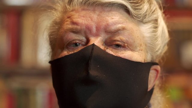 Senior person in medical face mask coronavirus home quarantine, elderly woman wearing reusable dustproof antibacterial mask close-up portrait.