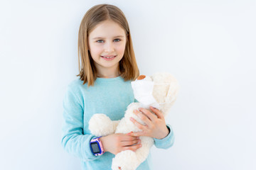 Smiling little girl with plush teddy in medical mask