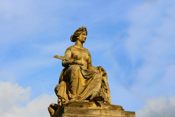 Stone figure of a woman mounted on the roof of an ancient building of the last century in Paris.