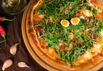 .pizza with arugula on a black wooden background