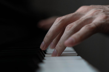 Fototapeta premium hands of a man playing the piano during the day, stylish photo