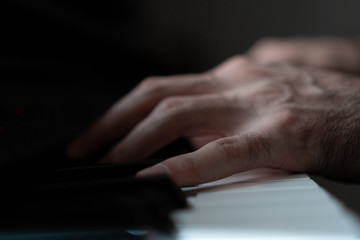 Fototapeta premium hands of a man playing the piano during the day, stylish photo