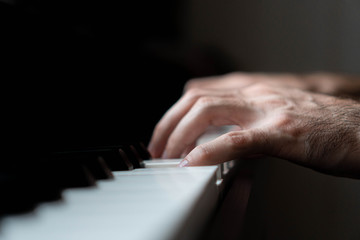 Fototapeta na wymiar hands of a man playing the piano during the day, stylish photo