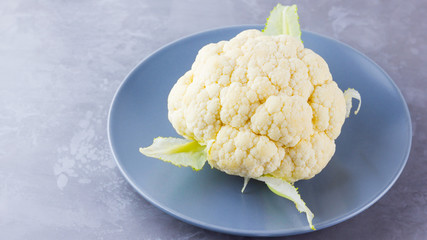 Cauliflower on a gray plate. Organic cauliflower on cement background. Vegan food. Minimalism. Copy...
