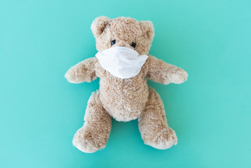 Plush teddy in medical face mask on blue background