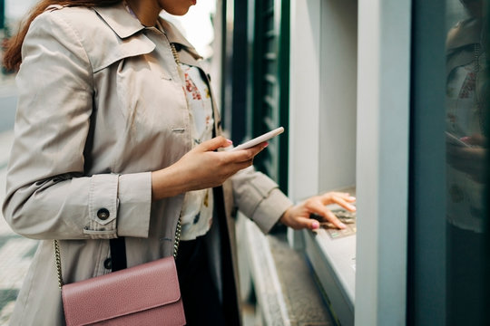 Woman Using Atm Machine And Mobile Phone