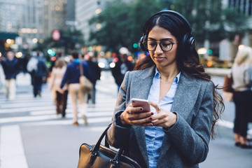 Contemporary young female using headphones for listening to music