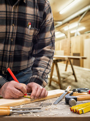 Close-up. Carpenter with pencil and the meter marks the measurement on a wooden board. Construction industry, carpentry workshop.