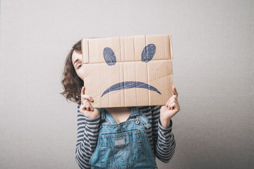 Young woman standing with a cardboard on his head with sad face