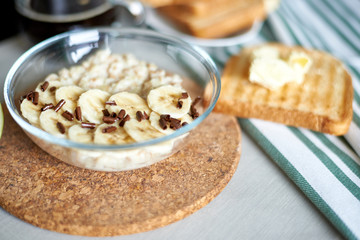 freshly cooked porridge with banana and toasts with butter