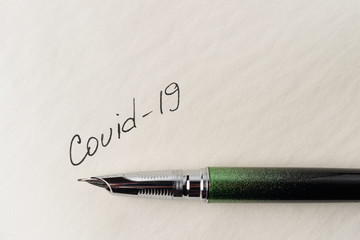 Covid-19 coronavirus inscription on a blank empty sheet of paper in a notebook. Nearby lies a pen....