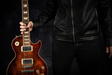 Eine rote E-Gitarre wird gehalten.