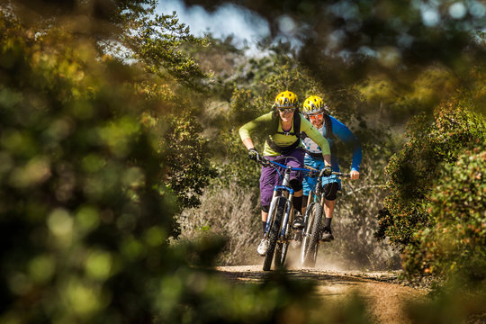 Man and woman on mountainbikes riding on dusty trail, Fort Ord National Monument Park, Monterey, California, USA