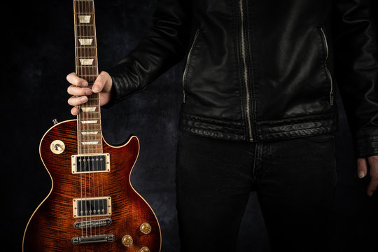 Eine rote E-Gitarre wird gehalten.