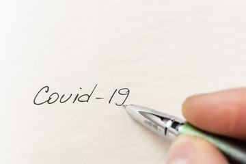 The hand writing coronbavirus on empty sheet . Covid-19 inscription on a blank empty sheet in...