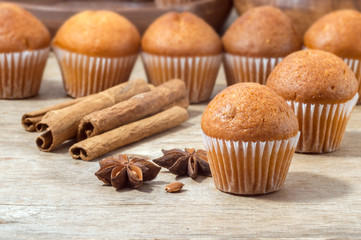 Small freshly mmuffins on a wooden table are ready to serve coffee. Sweet dessert. Cinnamon sticks and star anise.