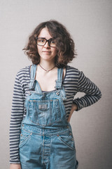 Woman in overalls dissatisfied stands with hand on hips. Gray background. - 336187625