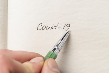 The hand writing coronbavirus on empty sheet . Covid-19 inscription on a blank empty sheet in...