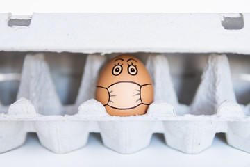 Chicken egg in a tray with doodle face wearing medical mask. Conceptual image of stay at home...