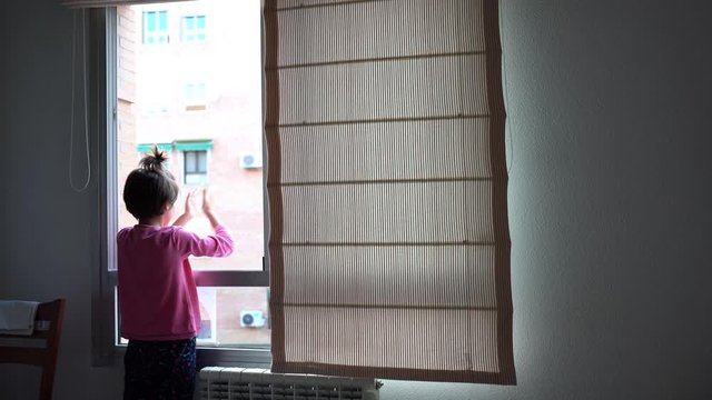 Girl clapping in the window in support of people who fight against the coronavirus