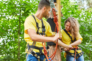 Naklejka na ściany i meble Woman and man in the high ropes course help each other