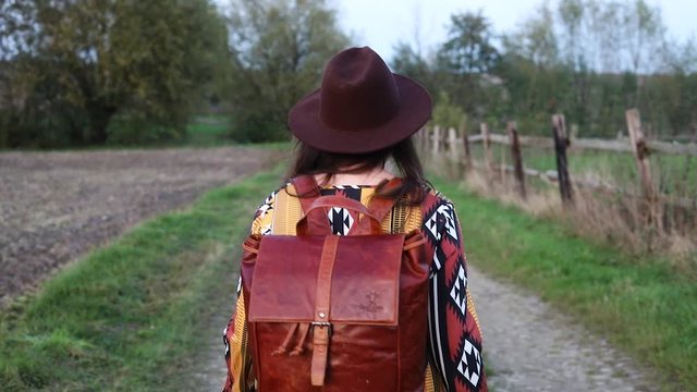  A woman traveler looks into the camera while hiking down a german field