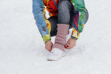 A young athletic girl ties her shoes on a frosty and snowy day. Fitness, running