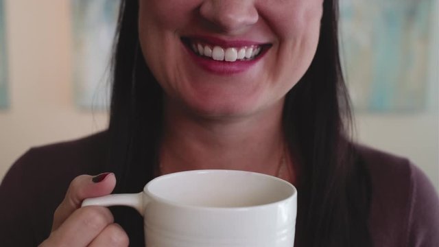 Female person drinking coffee from a big cup and smiling on a beautiful day,close up