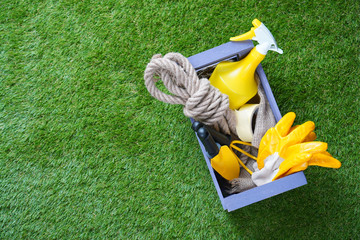 Gardening. Garden tools in the box on the green artificial grass.