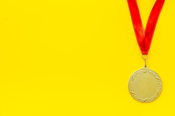 Gold medal with red ribbon - winner, success concept - on yellow background top view copy space