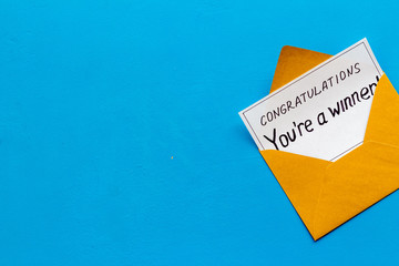 You're a winner. Envelope with congratulation card on blue table top view copy space