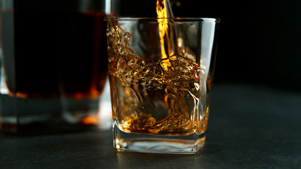 Splashing whiskey from glass with ice cubes inside