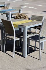 In April in Germany, in times of the corona pandemic, there are empty tables with empty chairs on the side of the road on an unpaved road in the sunshine