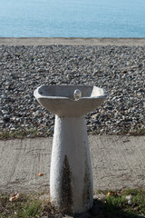 Fototapeta premium An old fountain with drinking water on the beach is not working. Closed season, pandemic, covid-19 coronavirus. Concept.