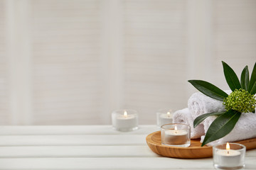 Fototapeta na wymiar Spa composition with aromatic candles and towel on white wooden table. Beauty spa treatment. copy space