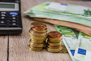 stacks of coins, calculator and euro on a wooden background. Close-up. Business concept.