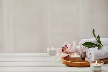 Poster Spa composition with aromatic candles, orchid flower and towel on white wooden table. Beauty spa treatment. copy space © producer