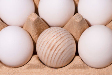 White eggs and one wooden were taken close-up in the package. The emphasis is on a wooden egg in the center. The photo was made especifically for your design.