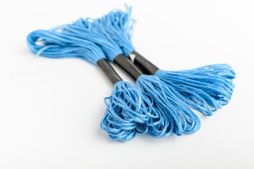 Three vivid blue sewing threads for embroidery isolated on a white table, side view of textile materials
