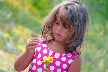 little girl in on a flower field with a bouquet of yellow flowers