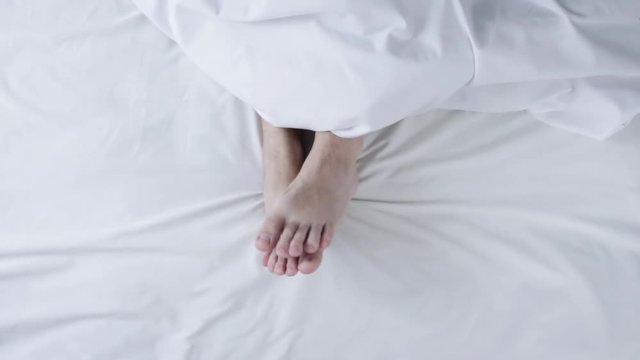 Male legs feet lying in bed, top view, morning waking up and relaxing.Lifestile concept