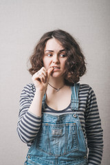 The woman lost in thought, chewing on nails from experiences fear. On a gray background.