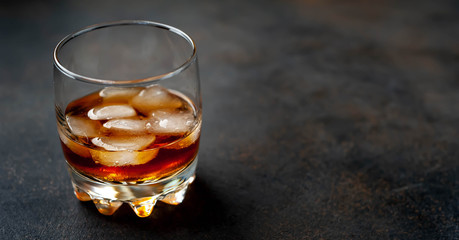 glass of whiskey with ice on a stone background with copy space for your text